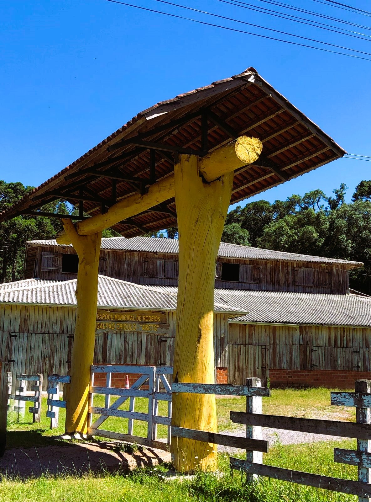 Porteira com telhado, ao fundo está um galpão